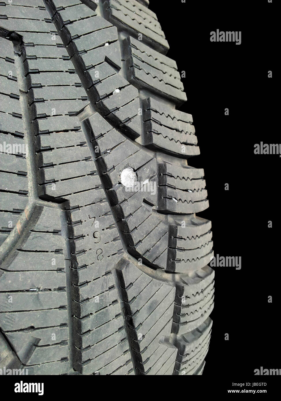 Screw into rubber tire isolated towards black background Stock Photo