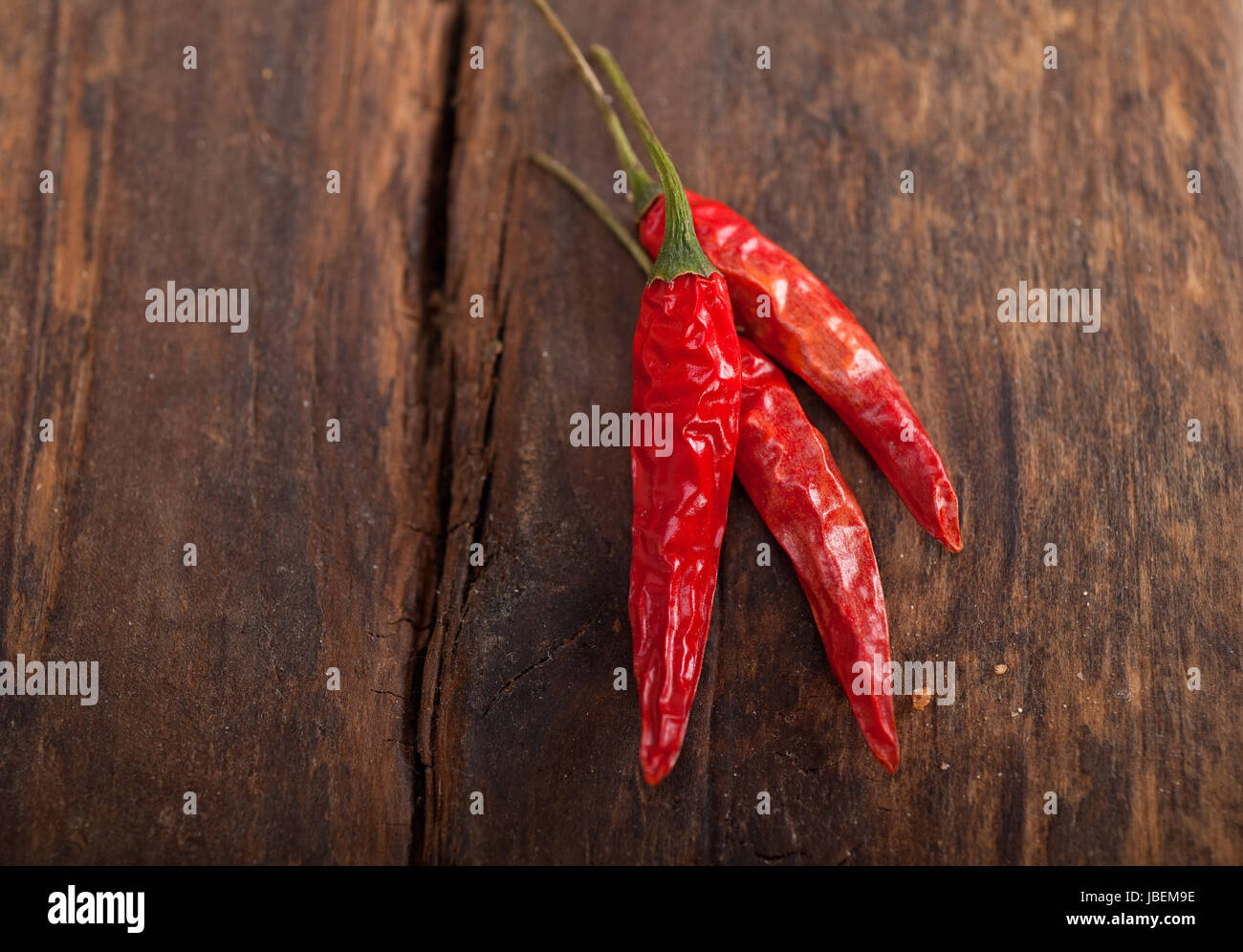 dry red chili peppers over old wood table Stock Photo - Alamy