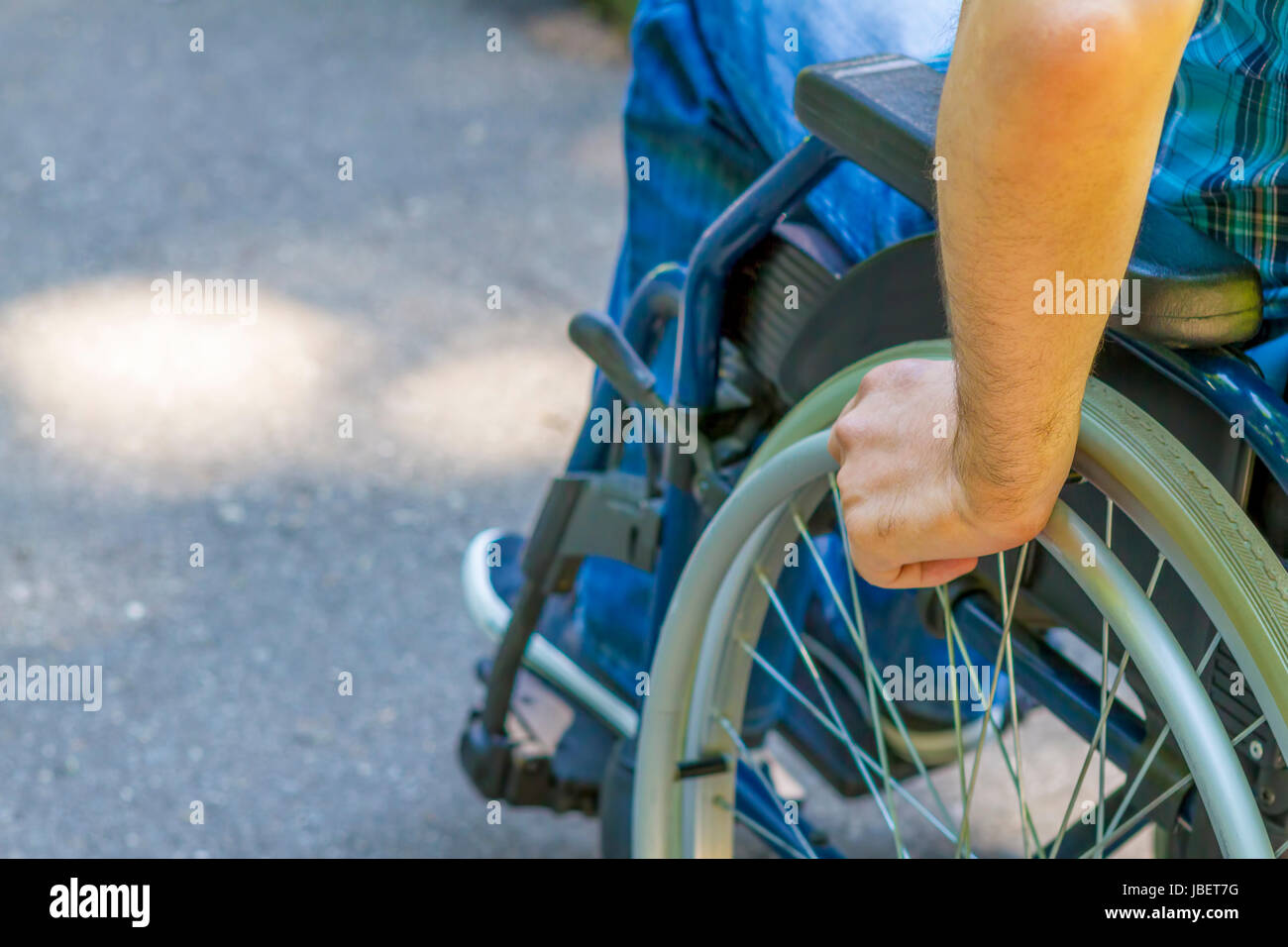 hand of young man on the wheel of wheelchair in the city park Stock Photo