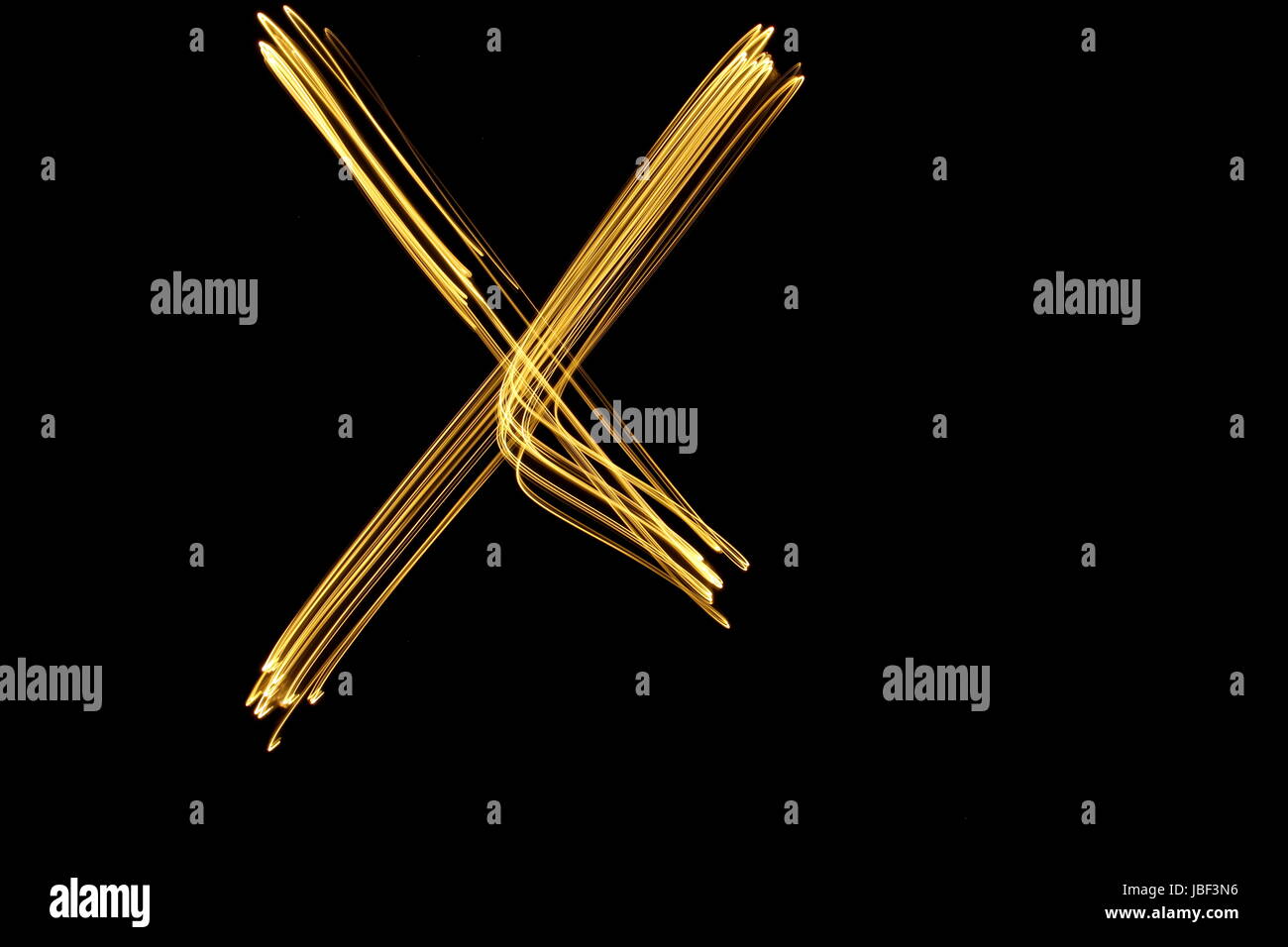 Gold letter X, Light Painting Photography, alphabet series, against a black background Stock Photo