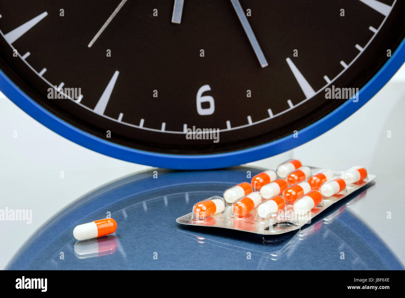 some pills and blue clock, daily medication treatment concept Stock