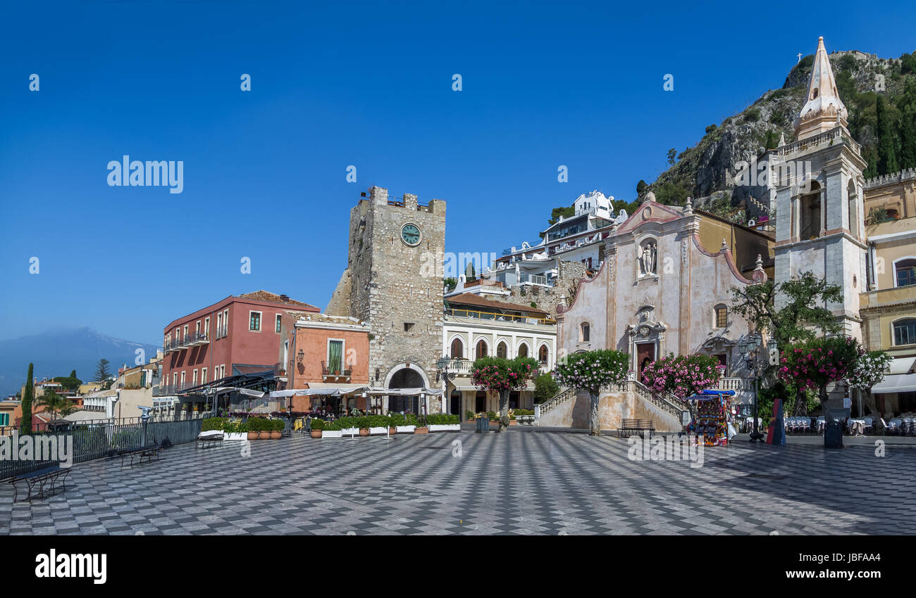 Panoramic view of Taormina main square (Piazza IX Aprile) with San Giuseppe Church, the Clock Tower and Mount Etna Volcano on background - Taormina, S Stock Photo