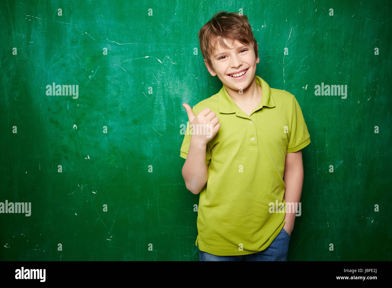 Portrait of smiling schoolboy showing thumb up while standing by the ...