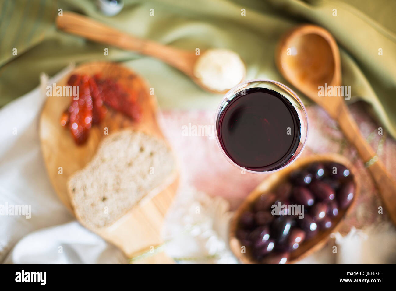 Red wine in glass from directly above with tapas out of focus on table. Stock Photo