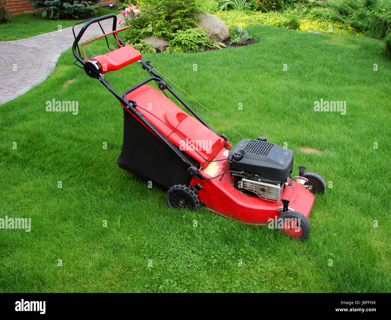 Gasoline powered lawn mower standing in extremely long grass Stock