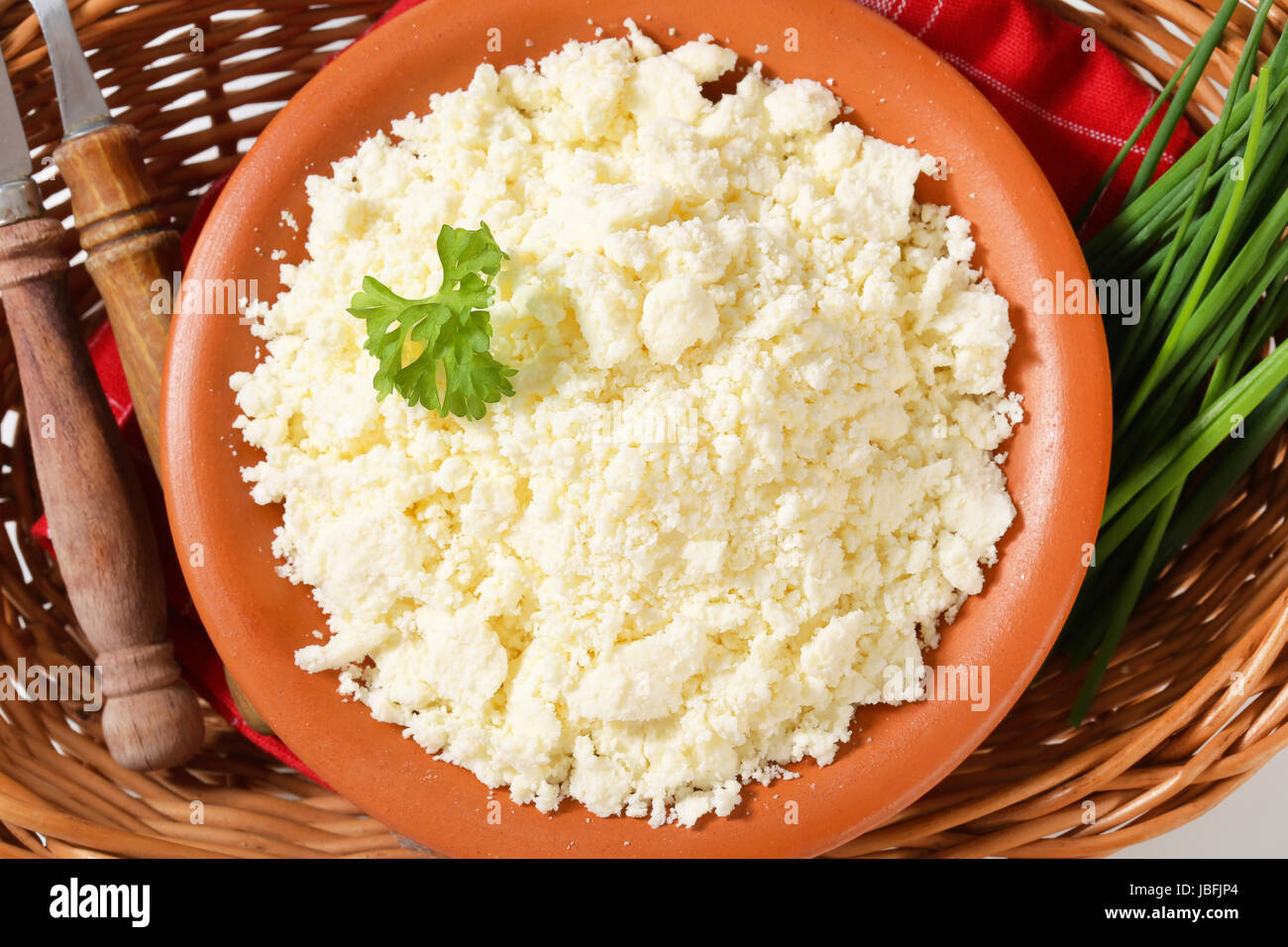 Bowl of Bryndza cheese and fresh chives in wicker basket Stock Photo