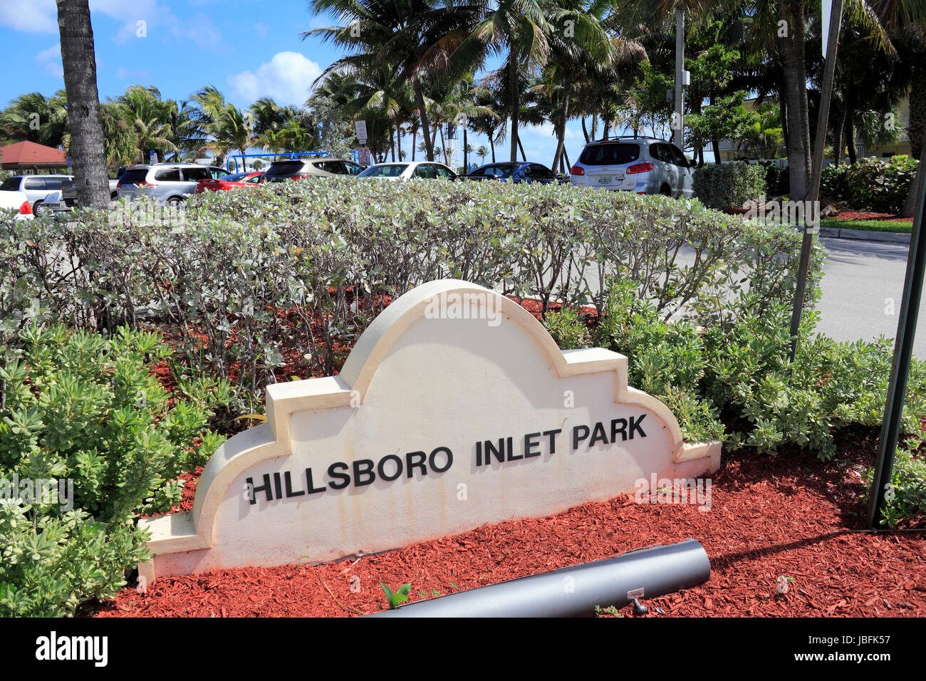POMPANO BEACH, FLORIDA - FEBRUARY 12, 2014: Entry sign to the left of opening to Hillsboro Inlet Park and parking where many vehicles are parked and is located near the lighthouse on a sunny day. Stock Photo