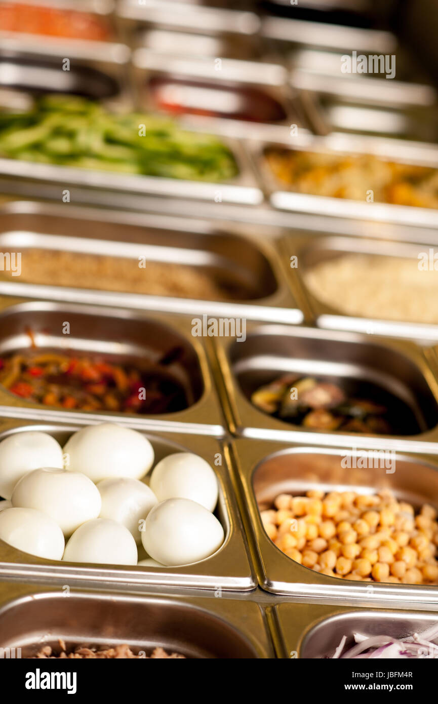 Assortment of food in trays laid out on a restaurant counter Stock