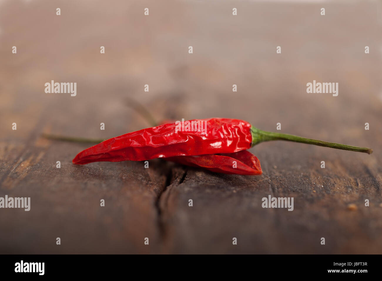 dry red chili peppers over old wood table Stock Photo - Alamy