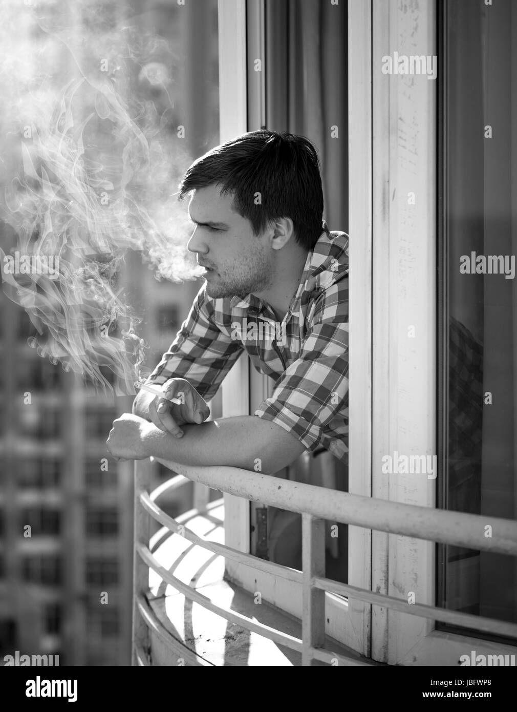 good looking depressed guy smoking a cigarette Monochrome portrait of depressed man smoking cigarette Stock Photo