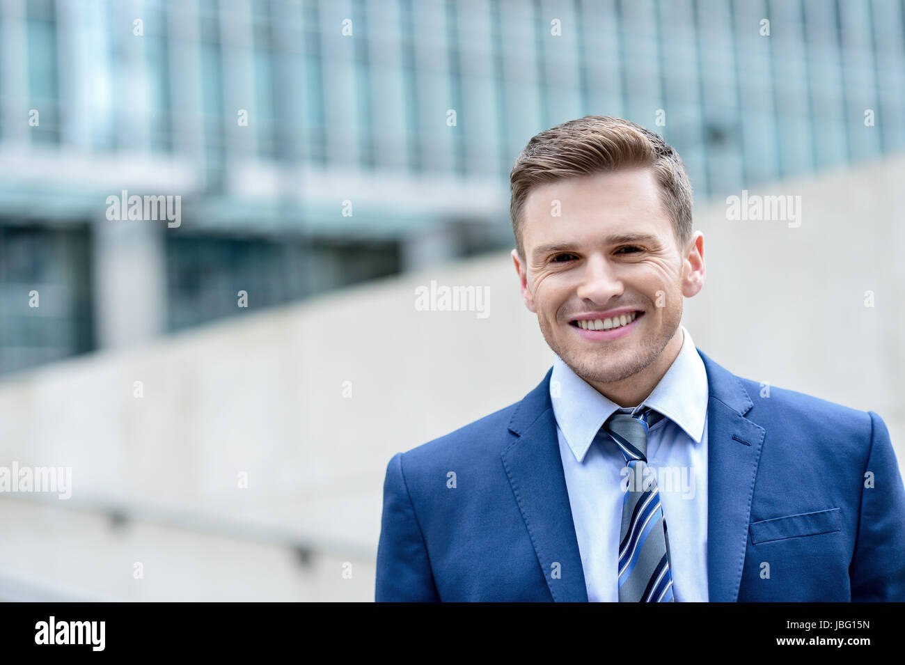 Young smiling man on modern building background Stock Photo - Alamy