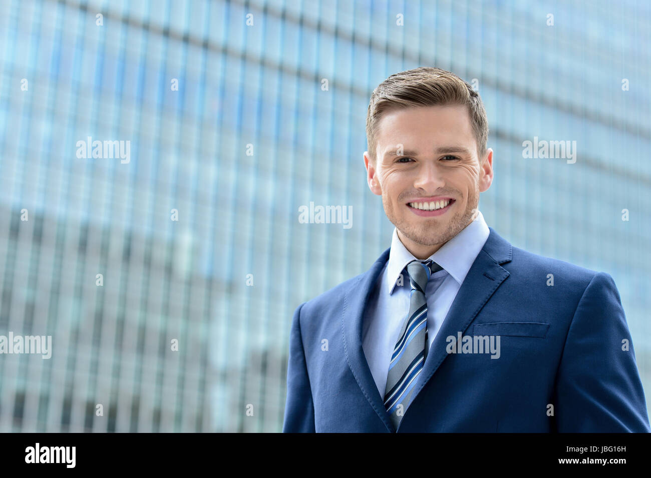 Smiling businessman standing outside of modern building Stock Photo - Alamy