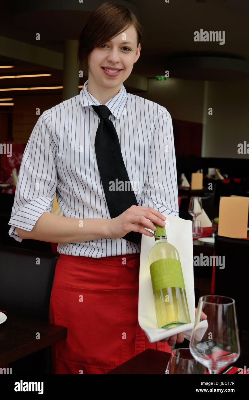 Kellnerin praesentiert mit Weinflasche eine Weinsorte Stock Photo
