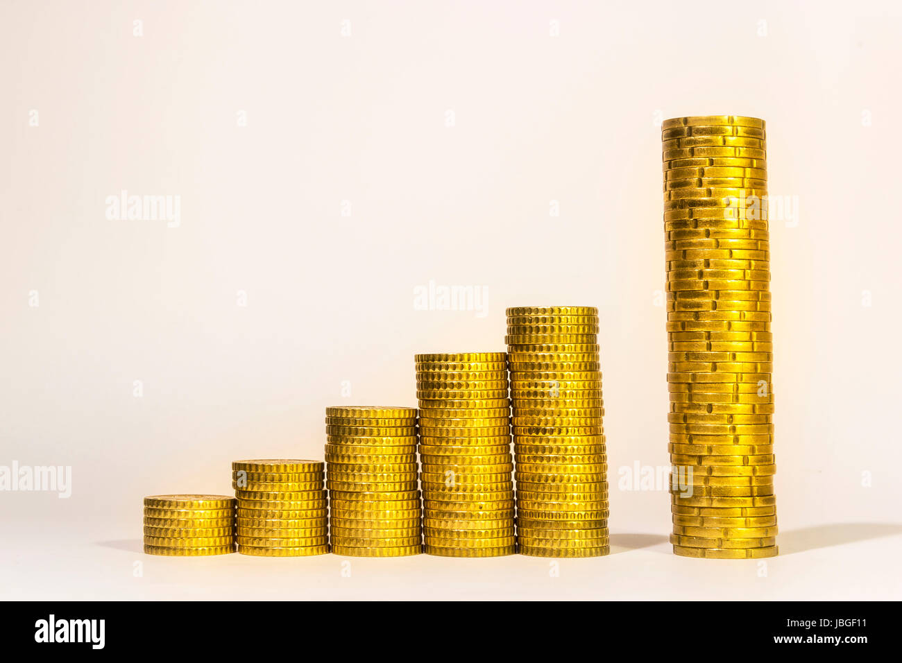 Yellow coins lined up from short to tall stacks with blank background