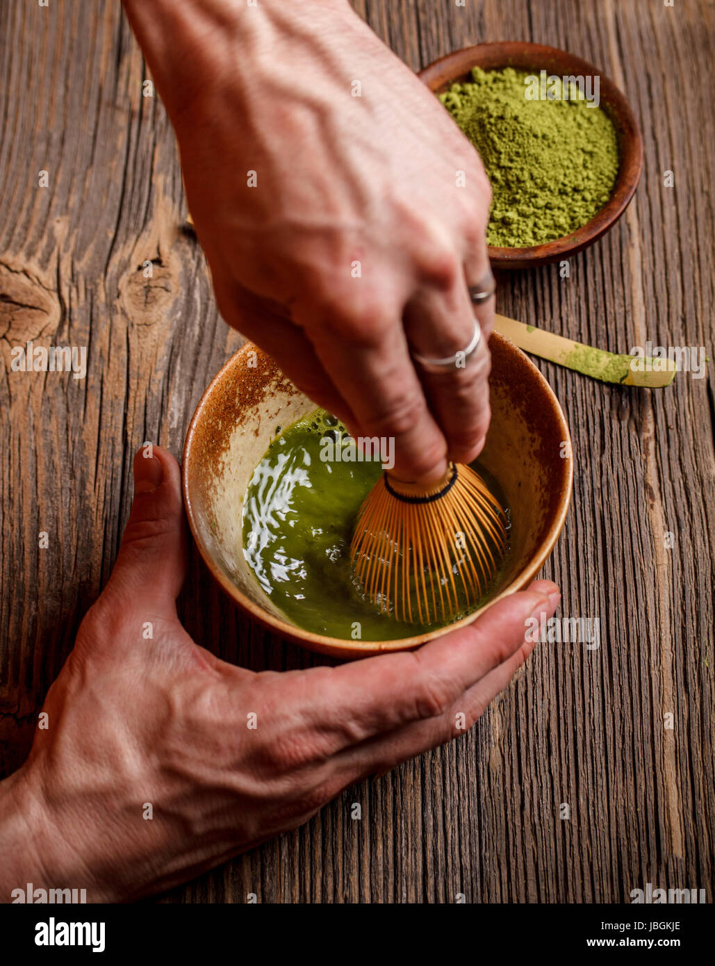 Beating matcha powder and water with bamboo whisk Stock Photo