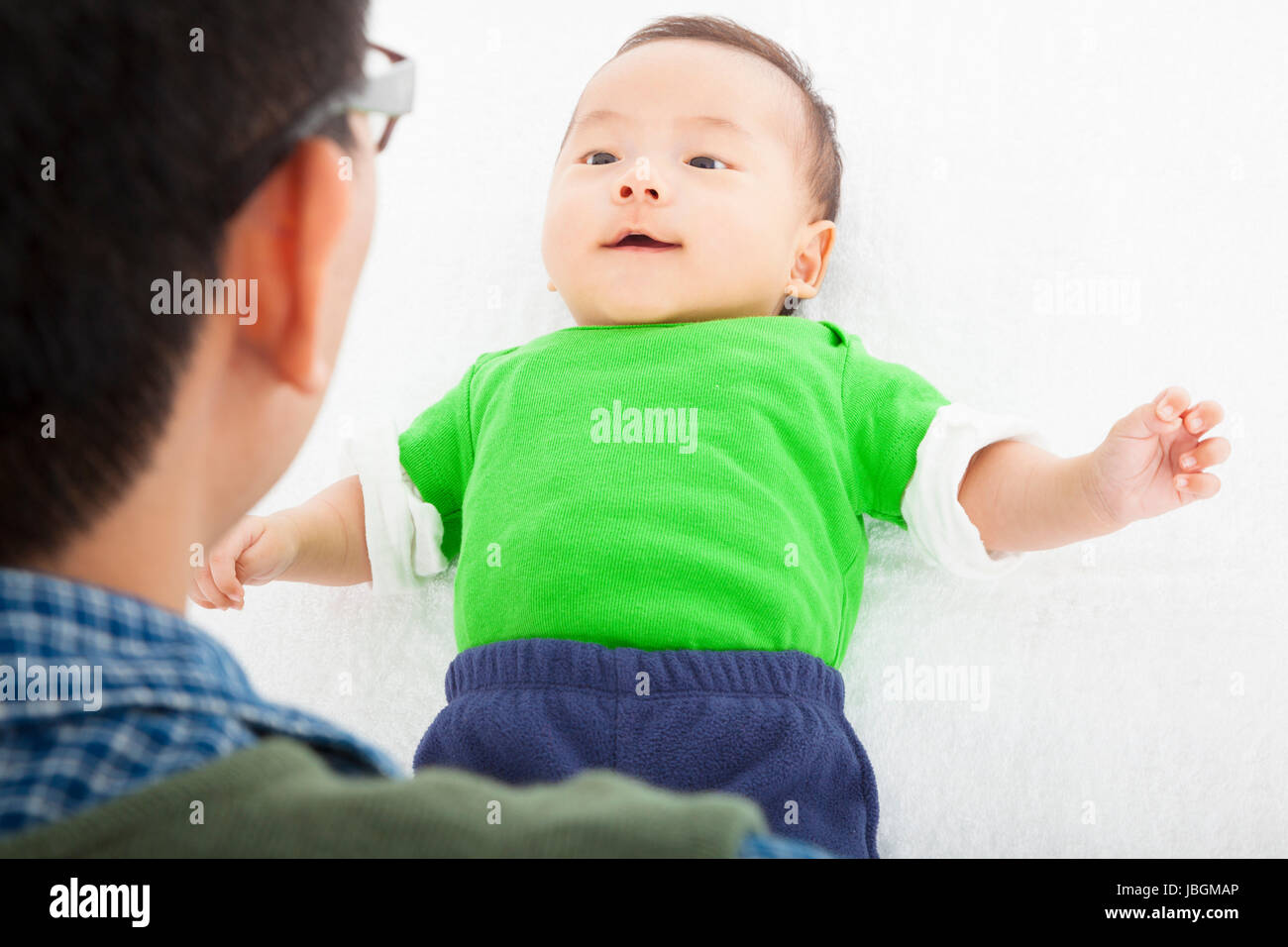 Young happy father playing with baby lying in bed Stock Photo - Alamy