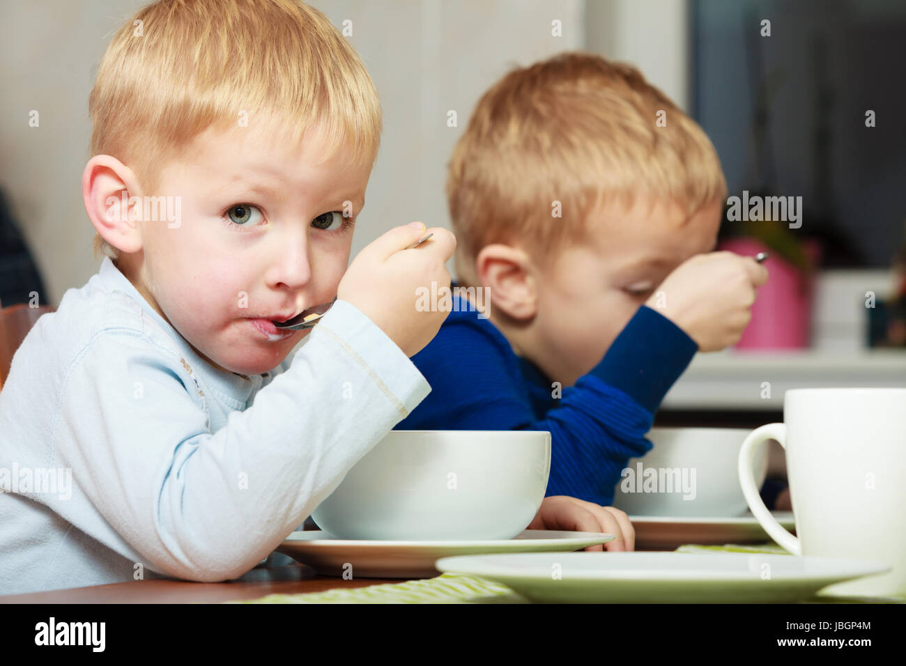 Two blond brothers boys kids children eating corn flakes breakfast