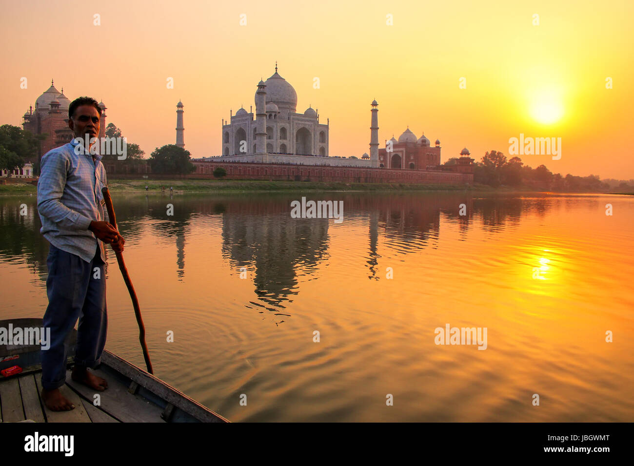 Local man steering boat on Yamuna river at sunset in front of Taj Mahal, Agra, India. It was build in 1632 by Emperor Shah Jahan as a memorial for his Stock Photo