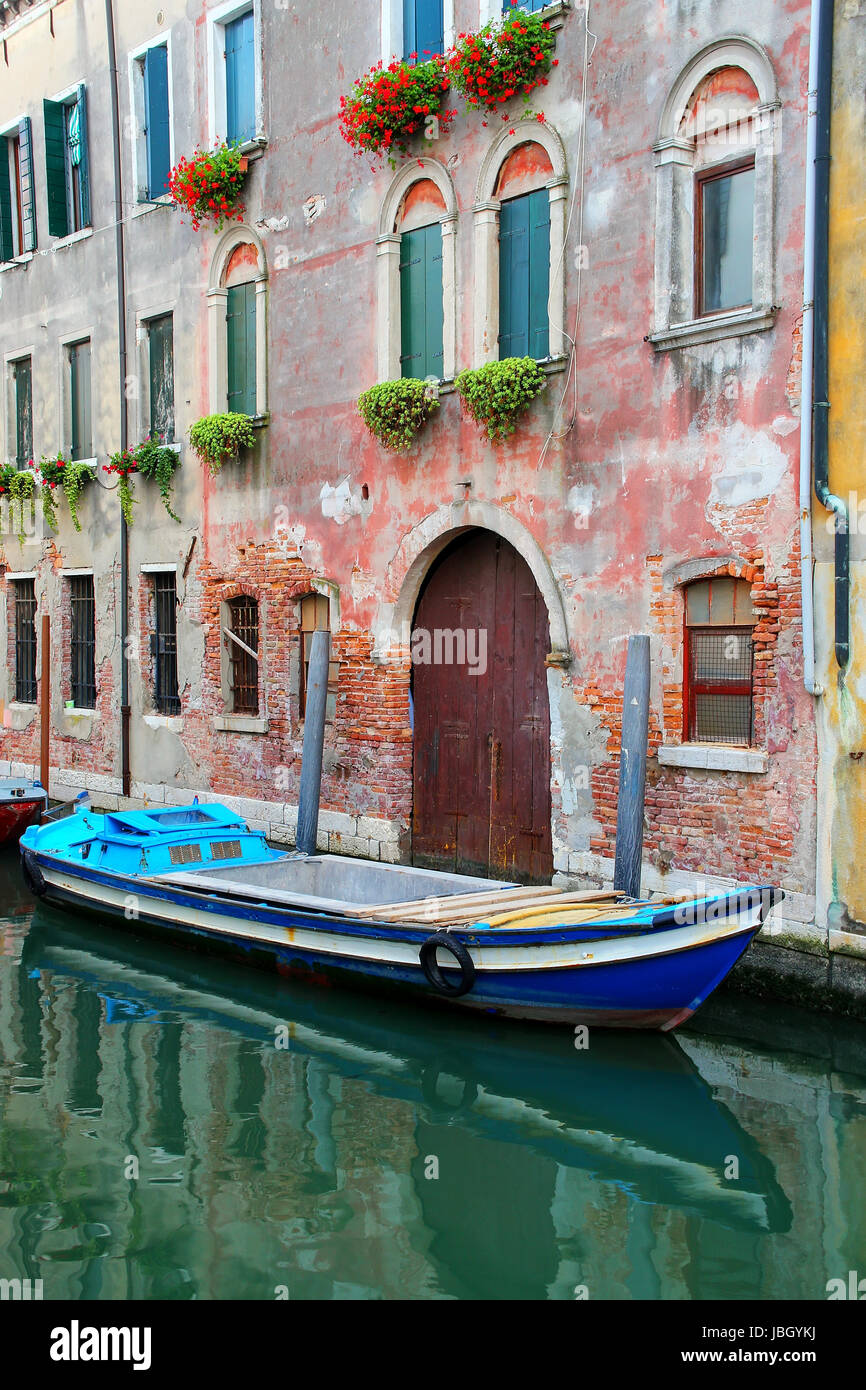 Boat moored in a narrow canal in Venice, Italy. Venice is situated across a group of 117 small islands that are separated by canals and linked by brid Stock Photo