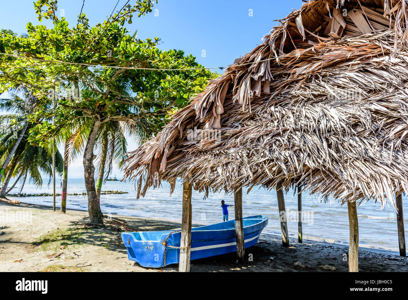 Livingston, Guatemala - August 31, 2016: Boat pulled ashore next to palapa on beach in Caribbean town of Livingston Stock Photo