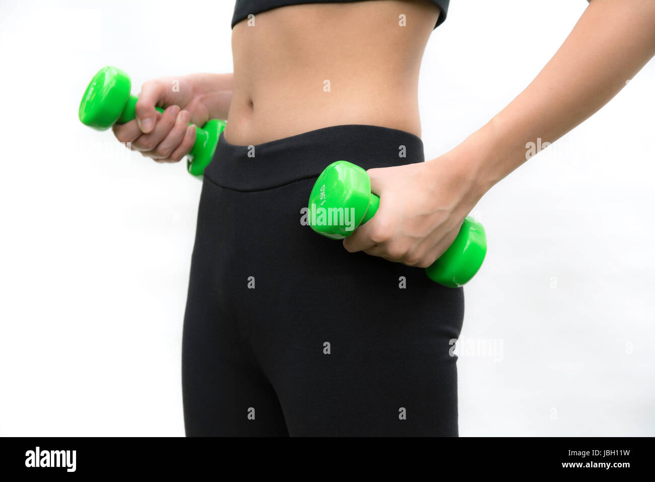 Attractive young fitness woman holding dumbbells isolated on white background. Stock Photo