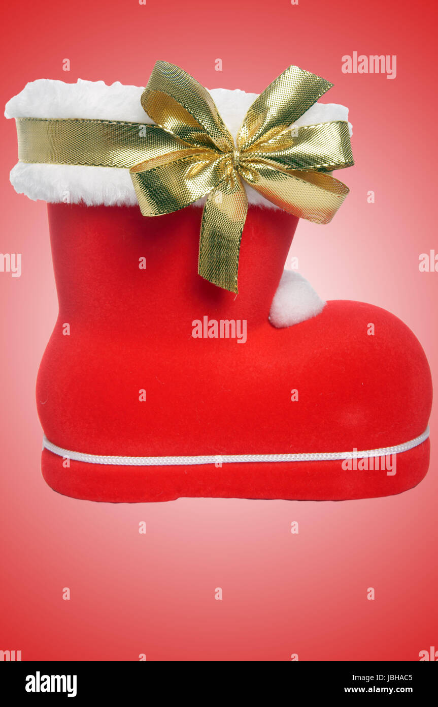 santa Claus Boot with golden ribbon over a red background Stock Photo