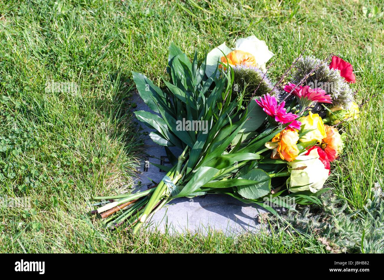 Schöner bunter Blumenstrauß auf einem Grabstein   Beautiful bouquet of flowers on a grave stone Stock Photo