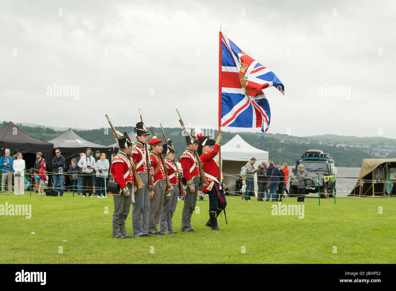 Dumbarton, West Dunbartonshire, Scotland, UK - 11 June 2017: UK weather - a Napoleonic soldier controlling a very large flag during Rock of Ages - a two day costume celebration of Scotland's history through the ages at Dumbarton Castle on a day of sunshine, gusty winds and showers Credit: Kay Roxby/Alamy Live News Stock Photo