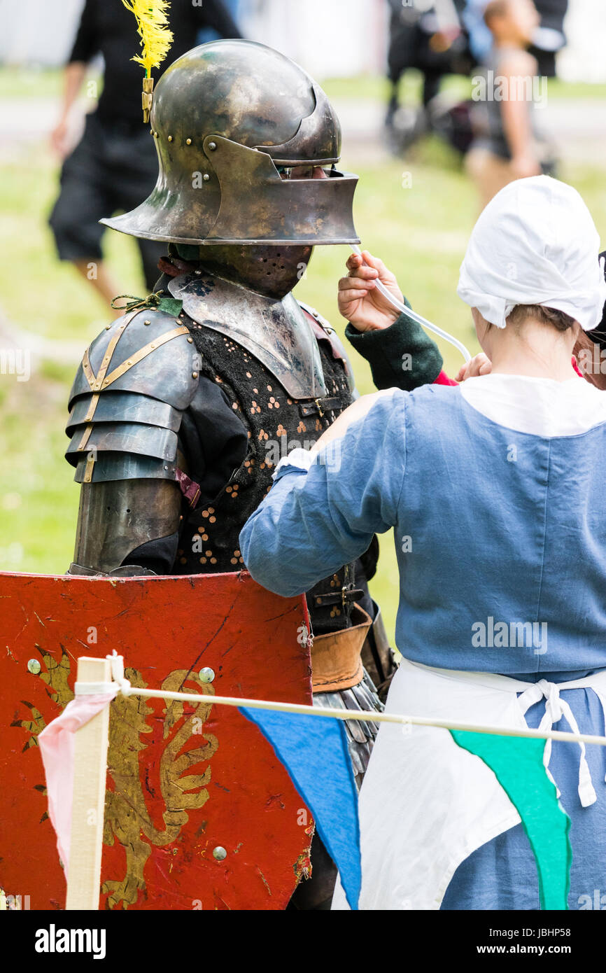 Knight standing in medieval suit of armour being given a drink via a long  tube held by a woman dressed in medieval clothing. Re-enactment living  history event Stock Photo - Alamy