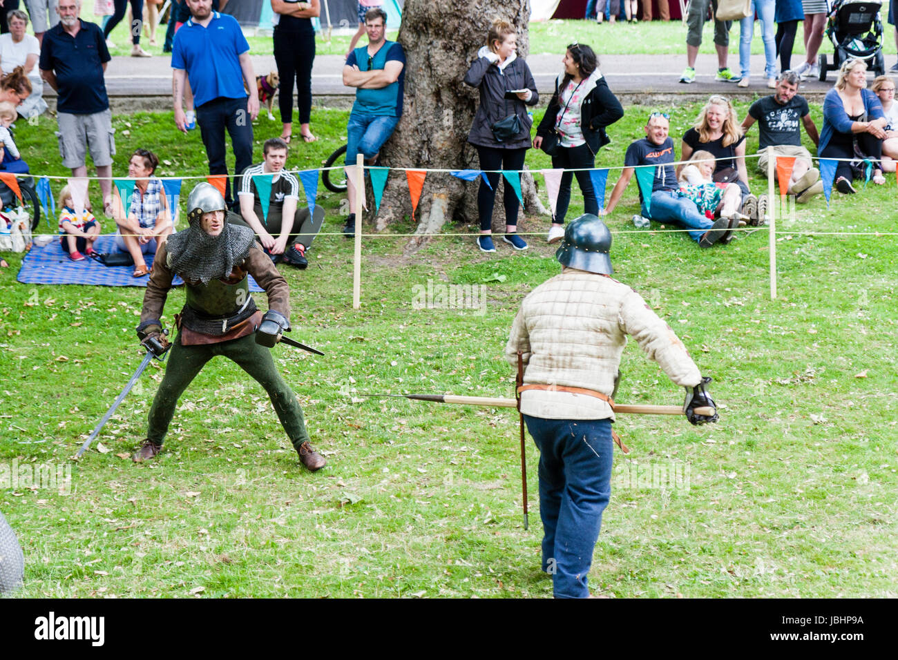 Medieval re-enactment event. Knights in armour fighting in small roped ...