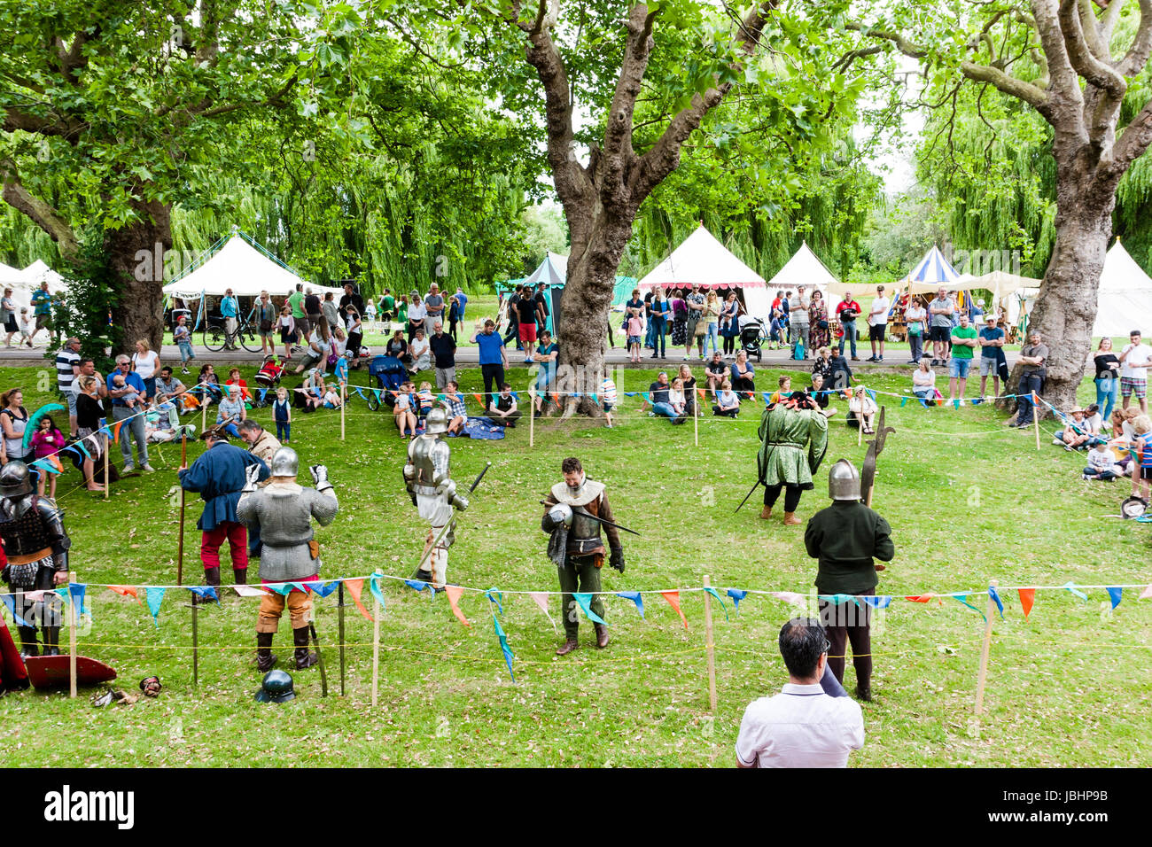 Medieval re-enactment event. Knights in armour fighting in small roped ...