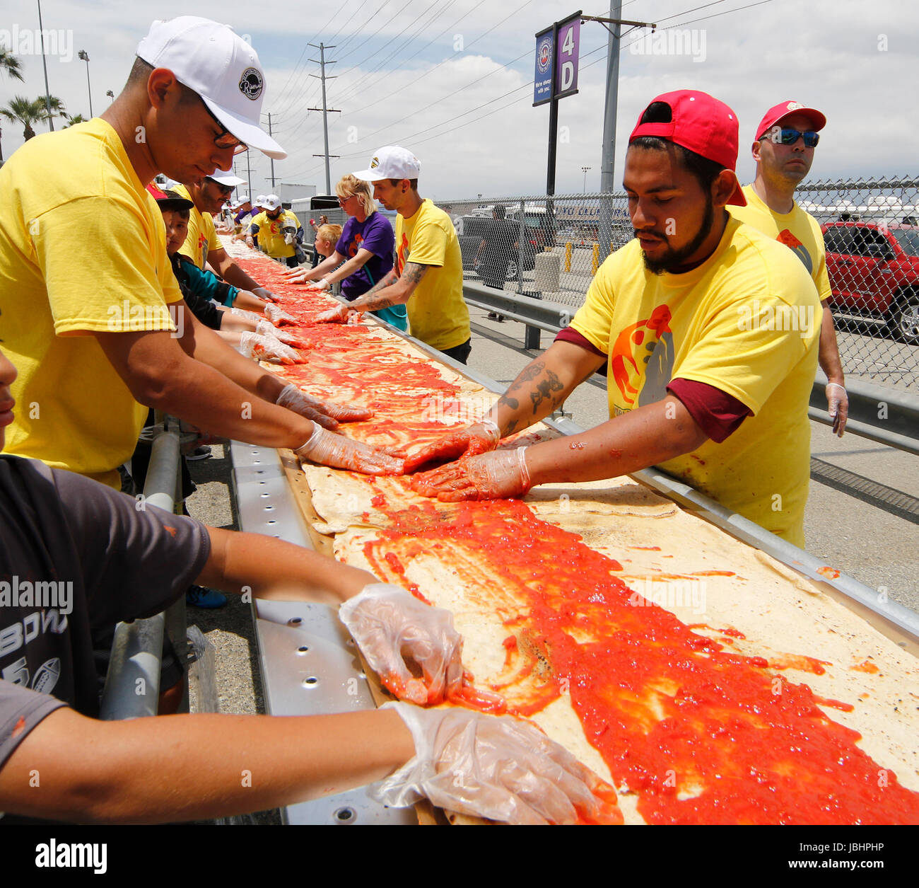 June 10, 2017. Fontana CA. The worlds longest pizza makes it into the Guinness Book of World Records as the 1.3 mile(6,820 ft) long pizza event took place at the Auto Club Speedway in Fontana California Saturday. The cooking of the pizza started at 11am and finish at 4pm outside the race track. The making of the pizza started Friday at 7pm with the pizza dough being made, cook and laid out along a 1.3 mile lone table. The making of the pizza consist of 530 gallons of tomato sauce, 20,000 pounds of dough, 15,000 pounds of cheese, 1.3 mile long table, 3 mobile pizza ovens, hundreds of pizza box Stock Photo