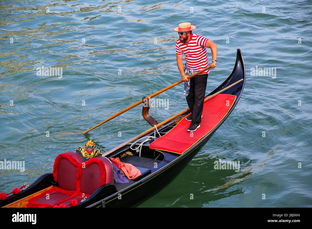 Man rowing gondola in Venice, Italy. Venice is situated across a group of 117 small islands that are separated by canals and linked by bridges. Stock Photo