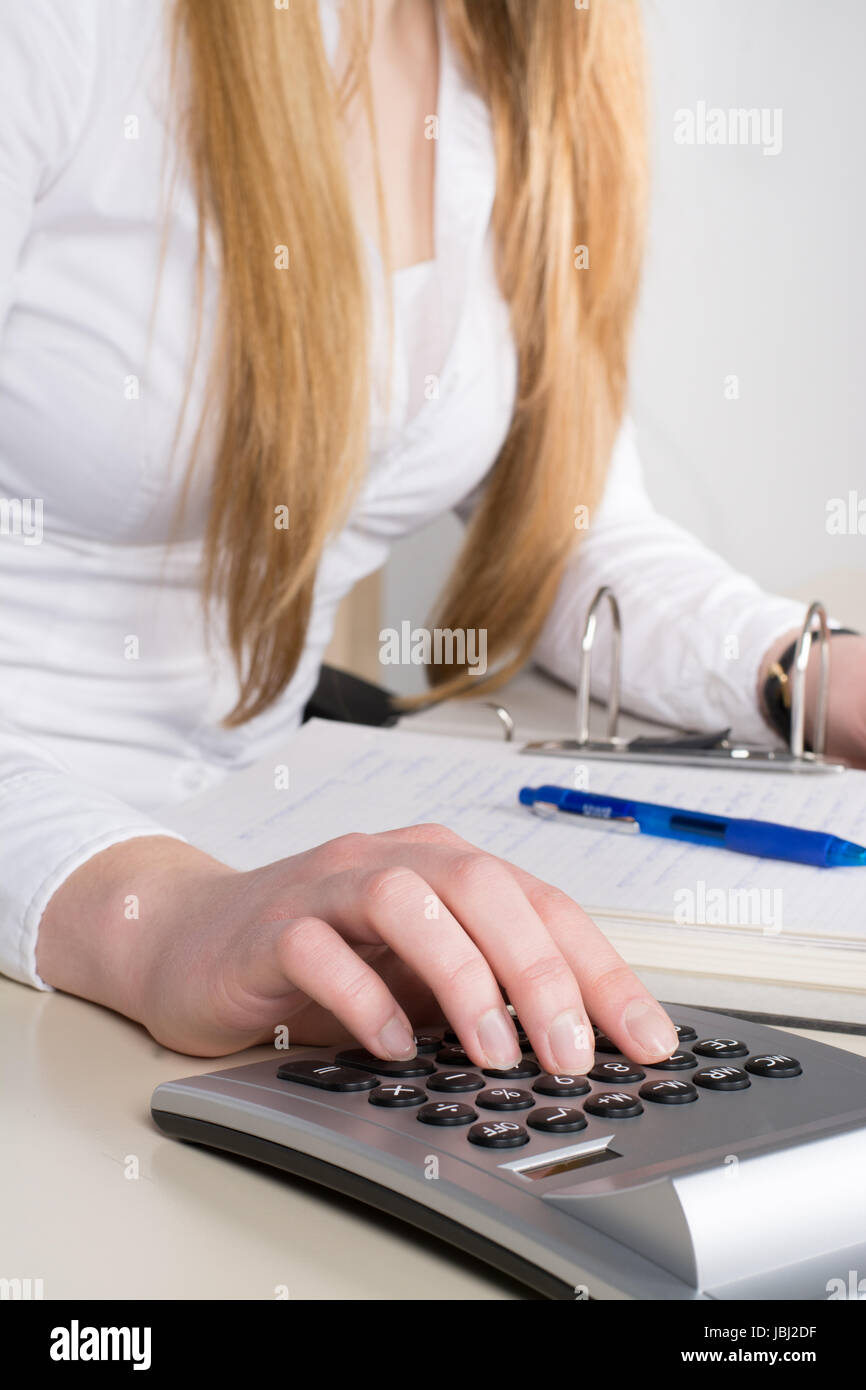 Frau sitzt am Schreibtisch und tippt auf einem Tischrechner. Focus liegt auf der Hand. Stock Photo