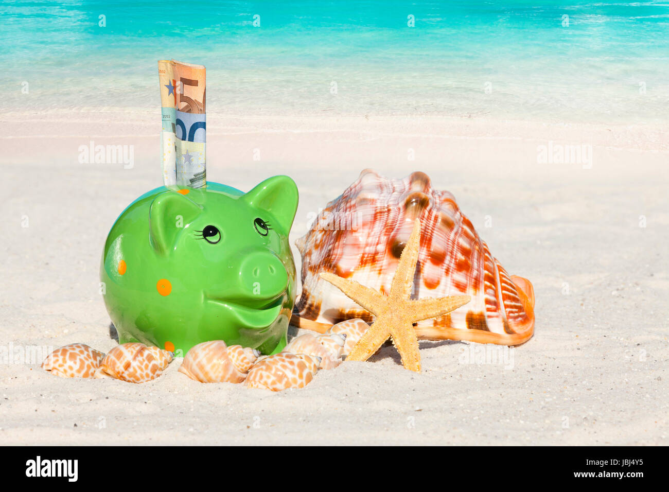 Grünes Sparschwein mit Geldscheinen am Sandstrand Stock Photo