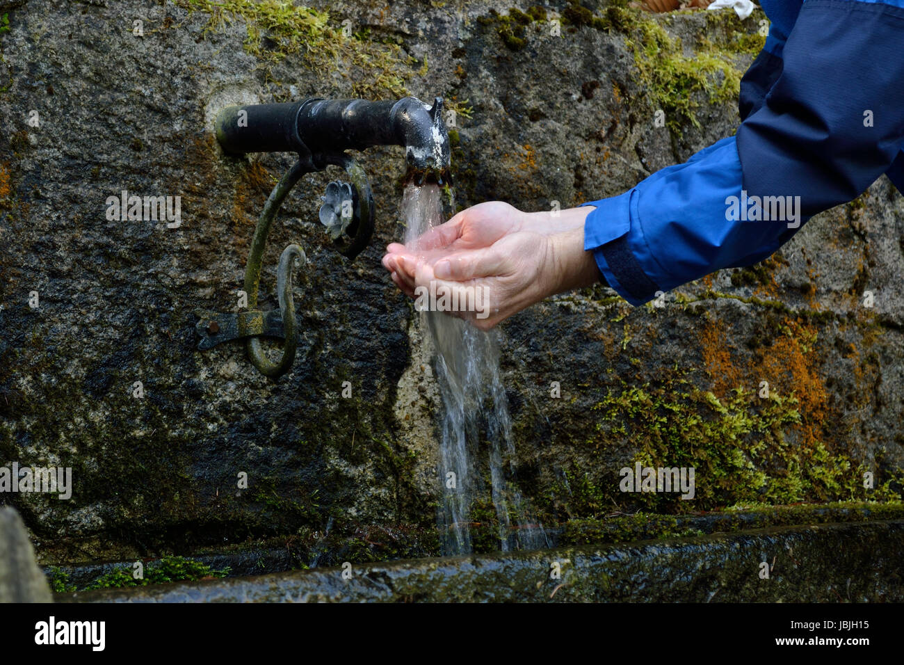 Person erfrischt sich im Freien bei einer Trinkwasserquelle Stock Photo