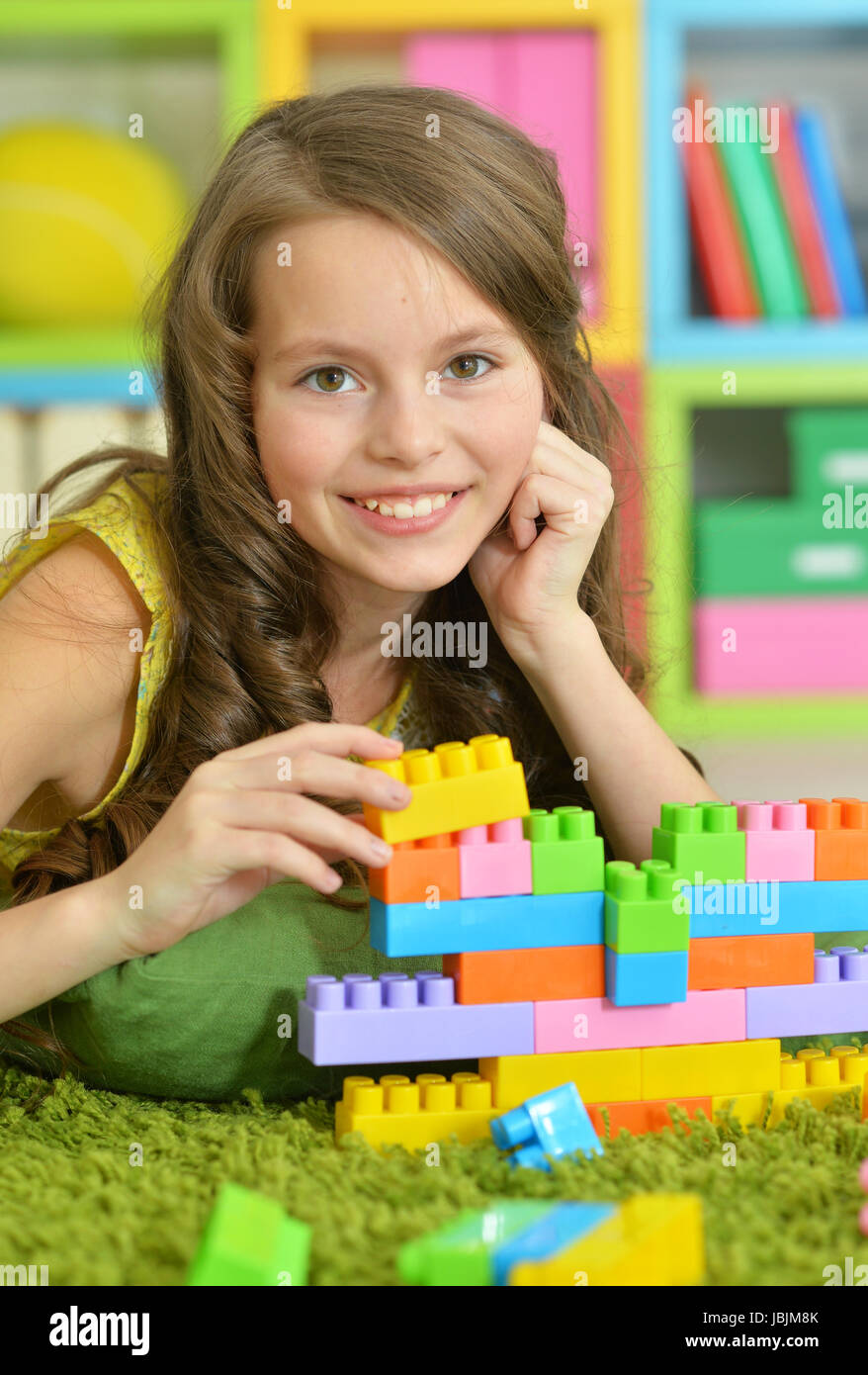 Cute girl playing with colorful plastic blocks in room Stock Photo - Alamy
