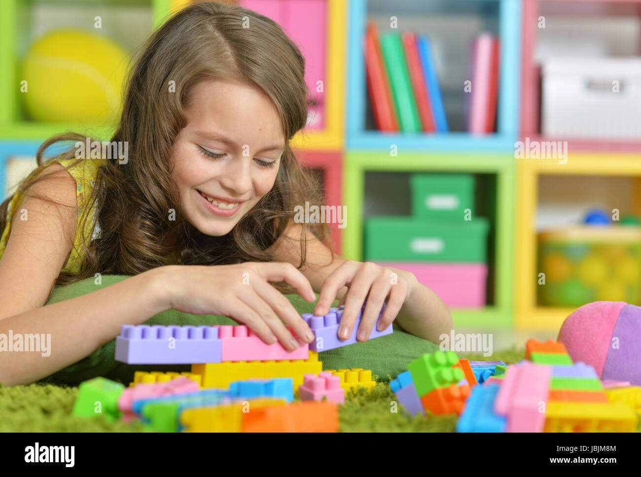 Cute girl playing with colorful plastic blocks in room Stock Photo - Alamy