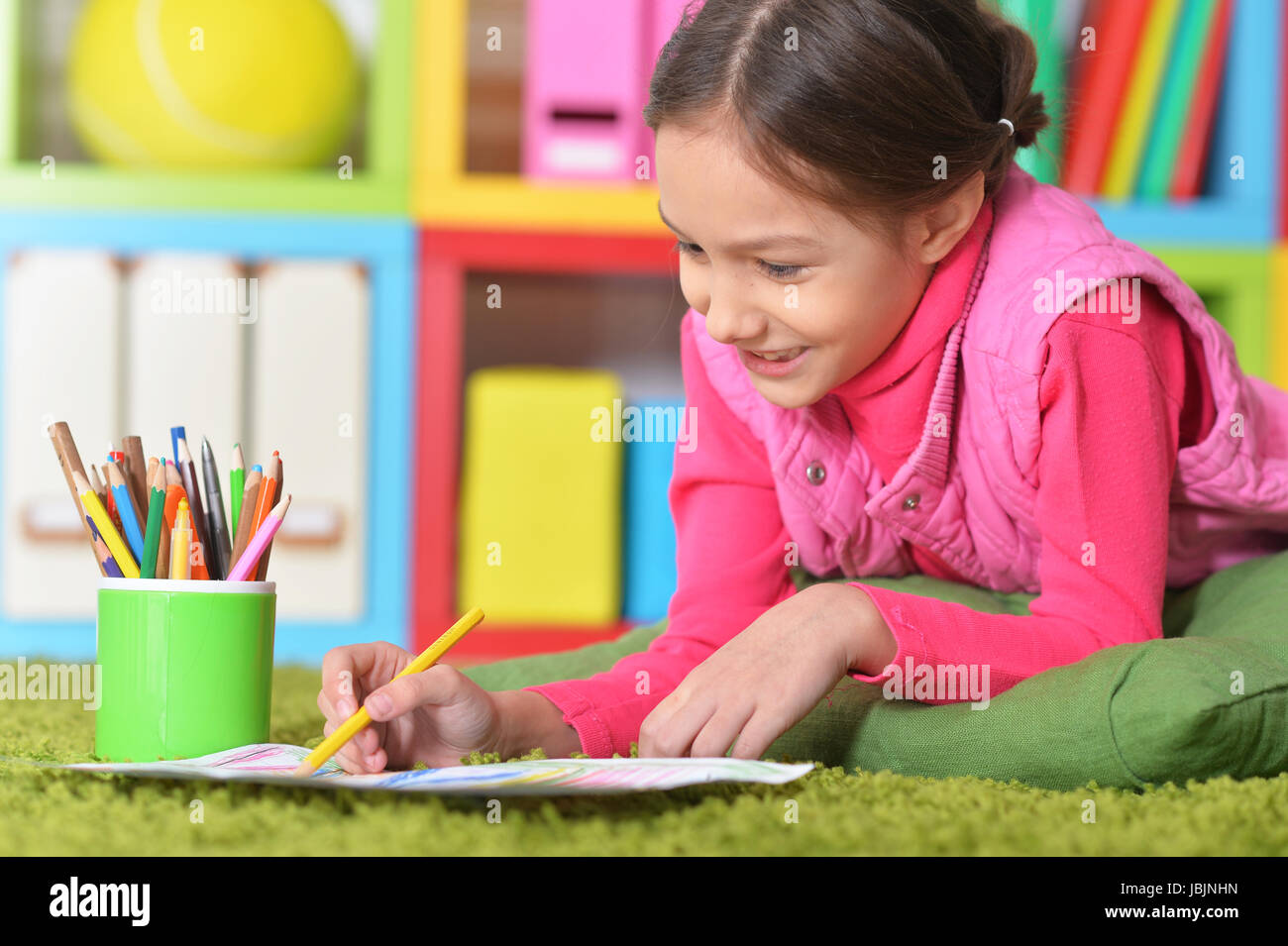 Cute little girl lying on floor and drawing picture Stock Photo - Alamy