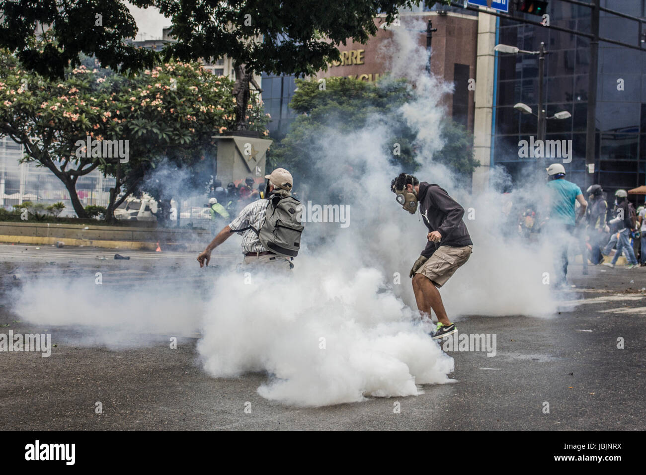 Elderly protester returning tear gas without gloves. An anti-government demonstrator is carried to safety during clashes with authorities in Caracas,  Stock Photo