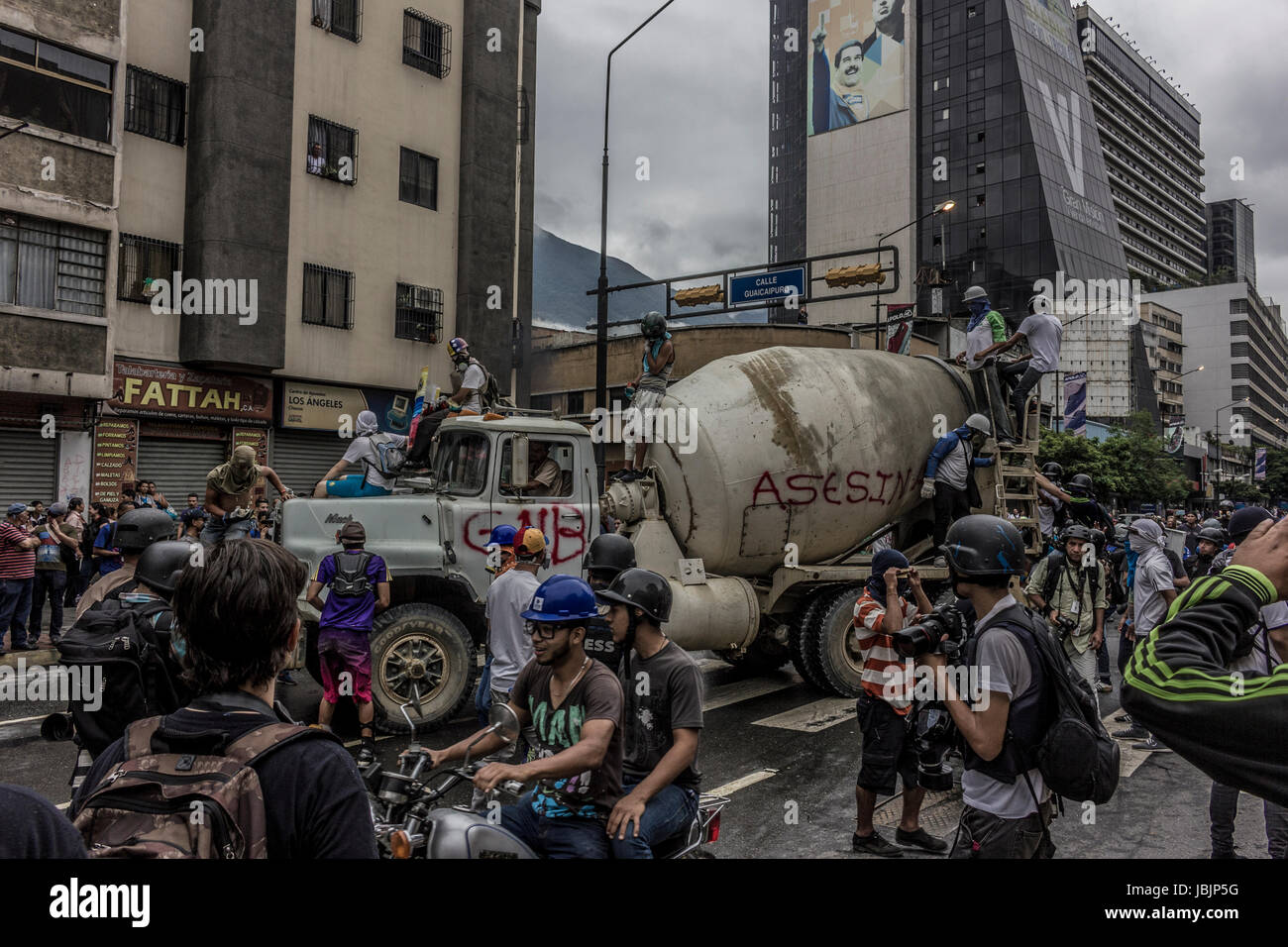 Protesters use cement mixer to lock up the National Guard (GNB). An anti-government demonstrator is carried to safety during clashes with authorities  Stock Photo