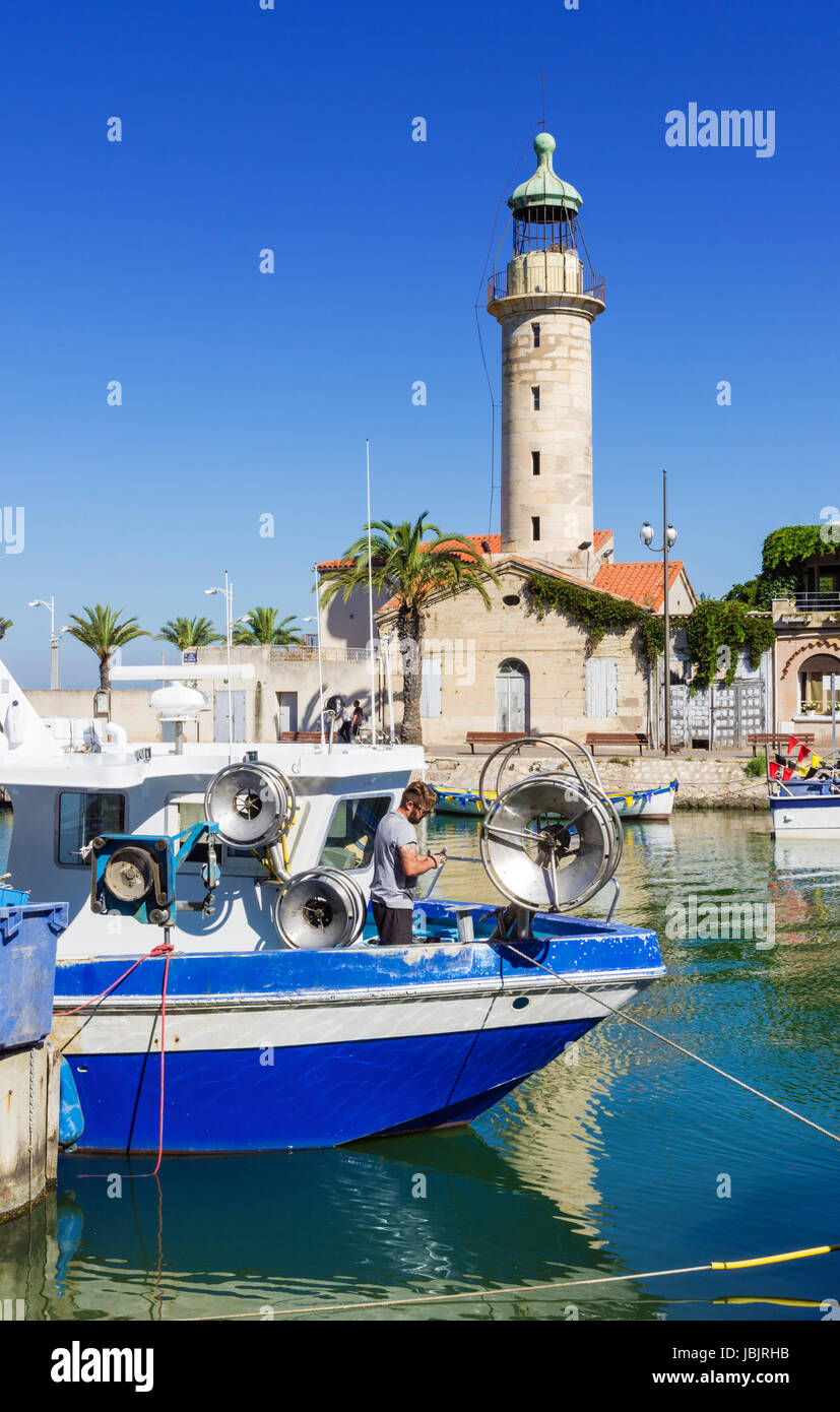 Moored fishing boats and the landmark stone lighthouse along the Chenal Maritime, Le Grau-du-Roi, Gard, France Stock Photo