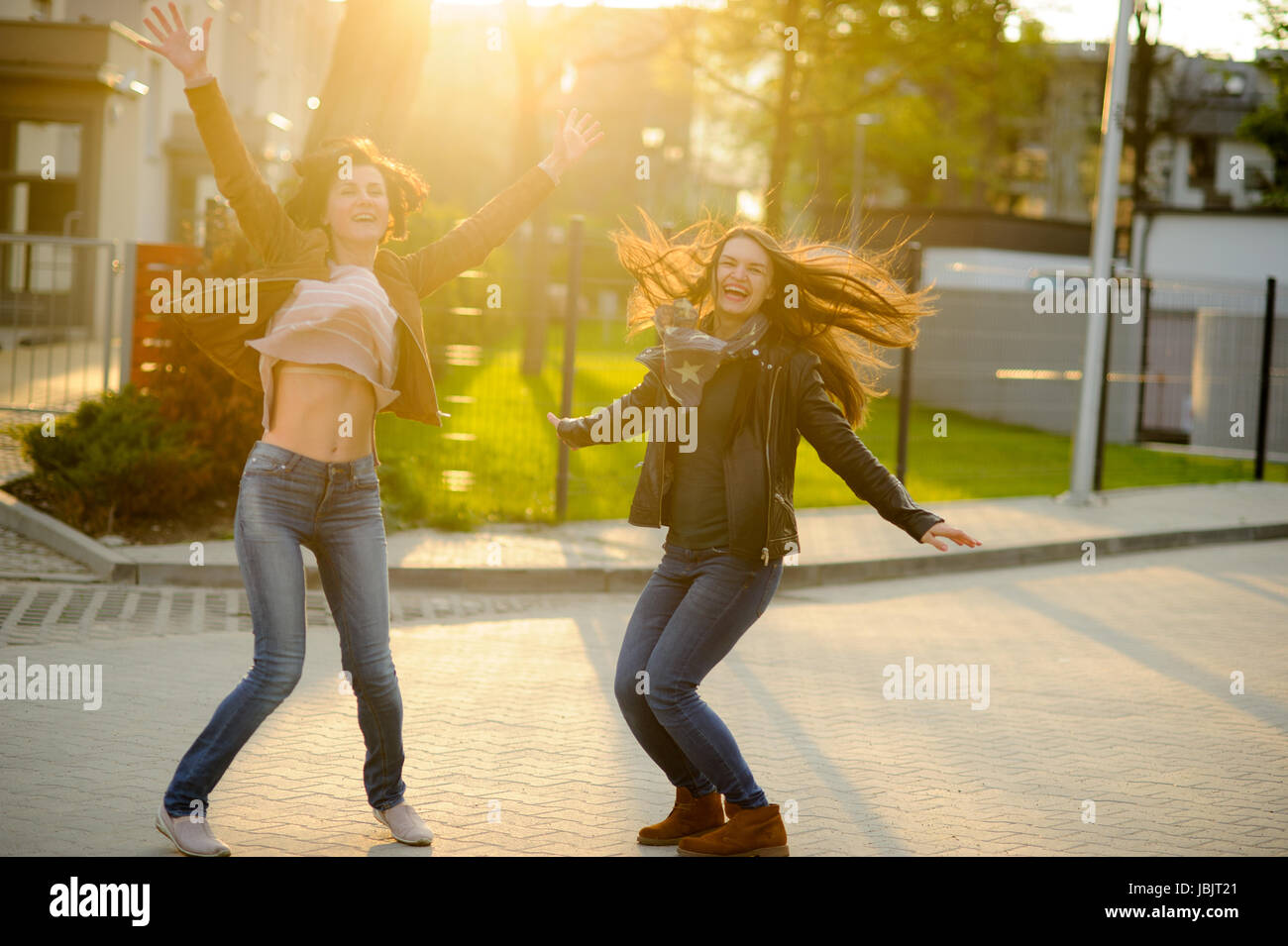 Two cheerful young women. Girlfriends dance. Wonderful spring day ...