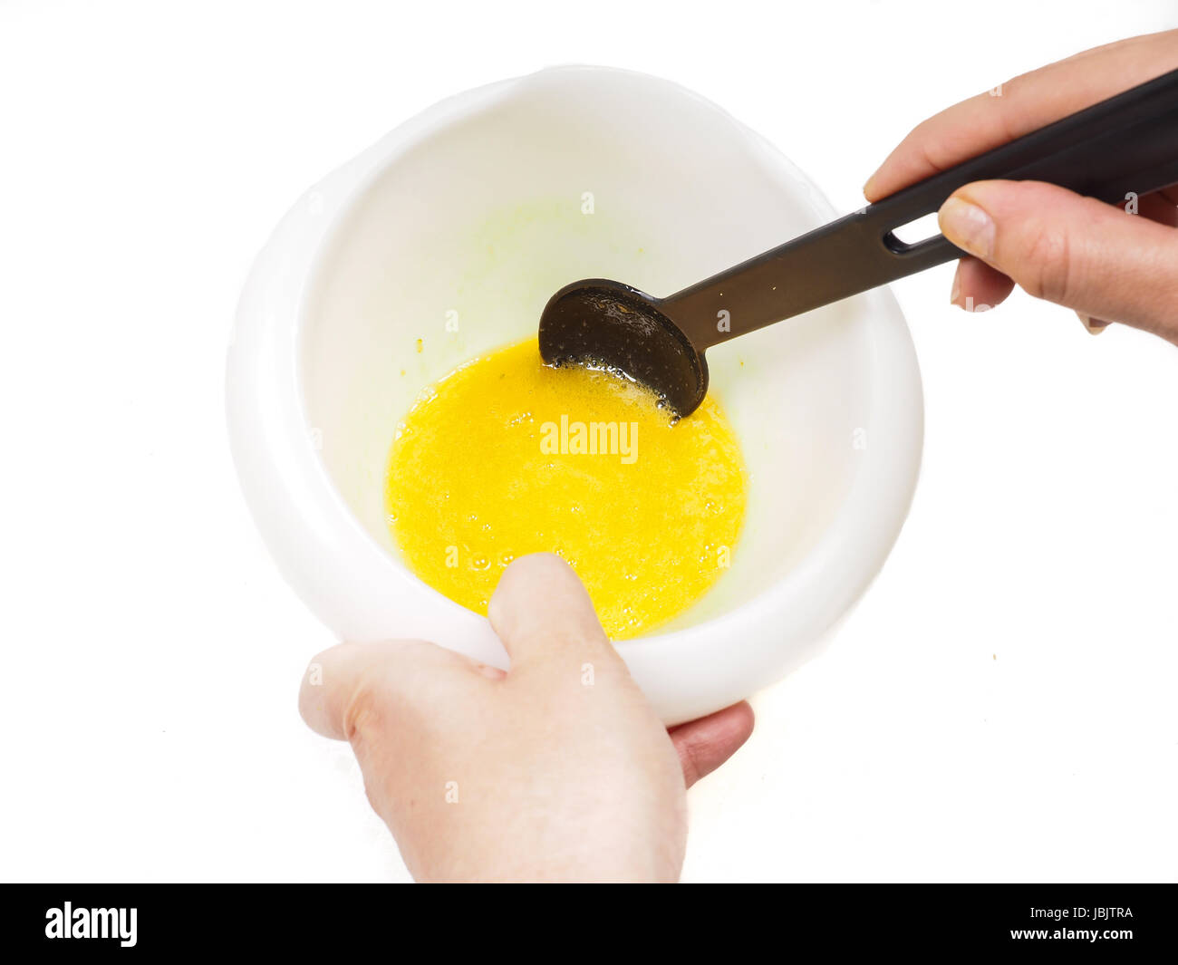 Female person mixing egg yolk and melted butter in a white bowl with a