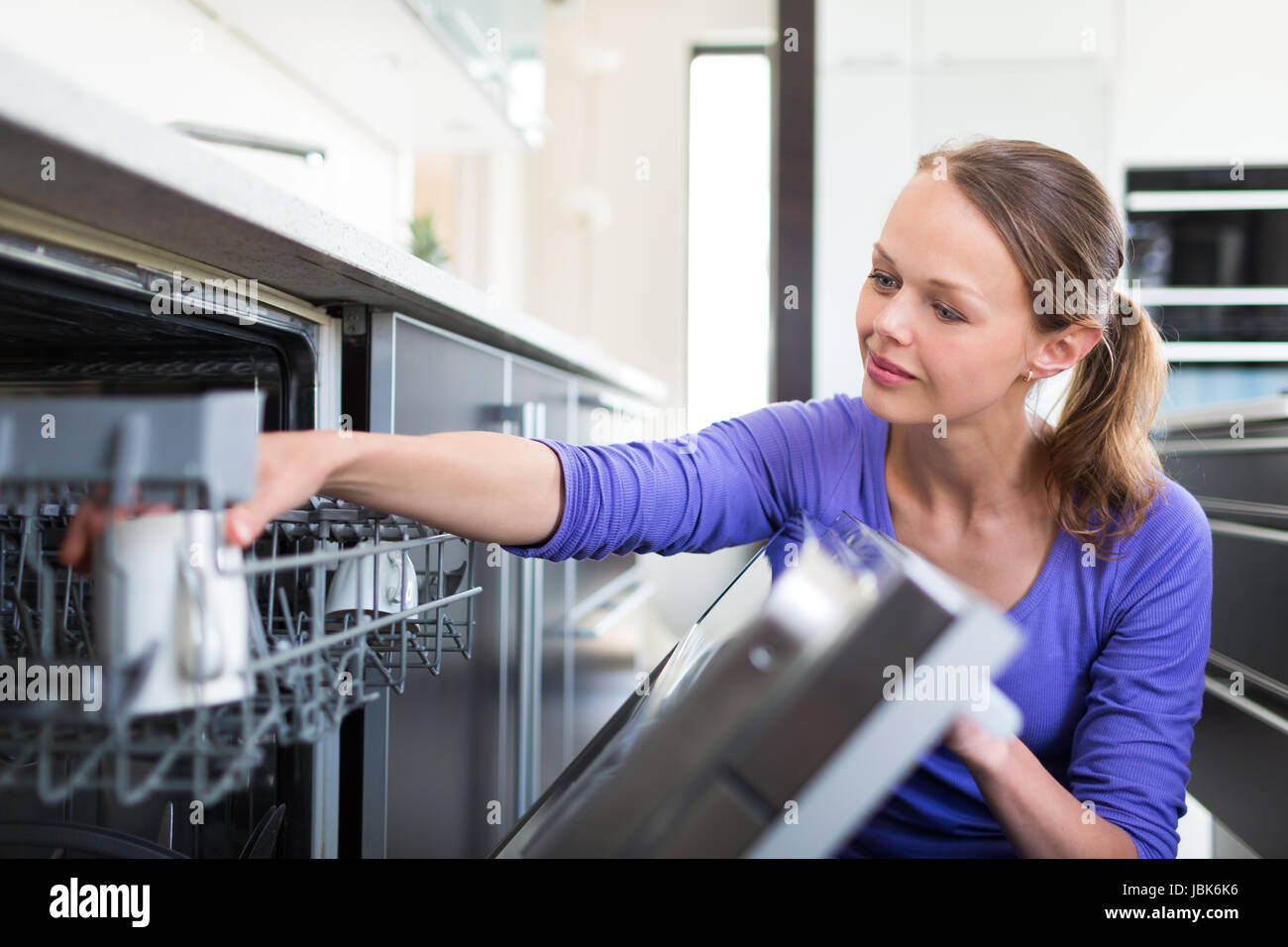 Housework young woman putting dishes in the dishwasher Stock Photo Alamy