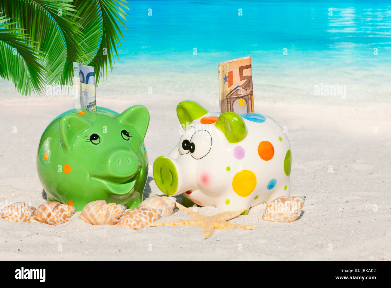 Zwei Sparschweine mit Geldscheinen unter Palmwedel Stock Photo