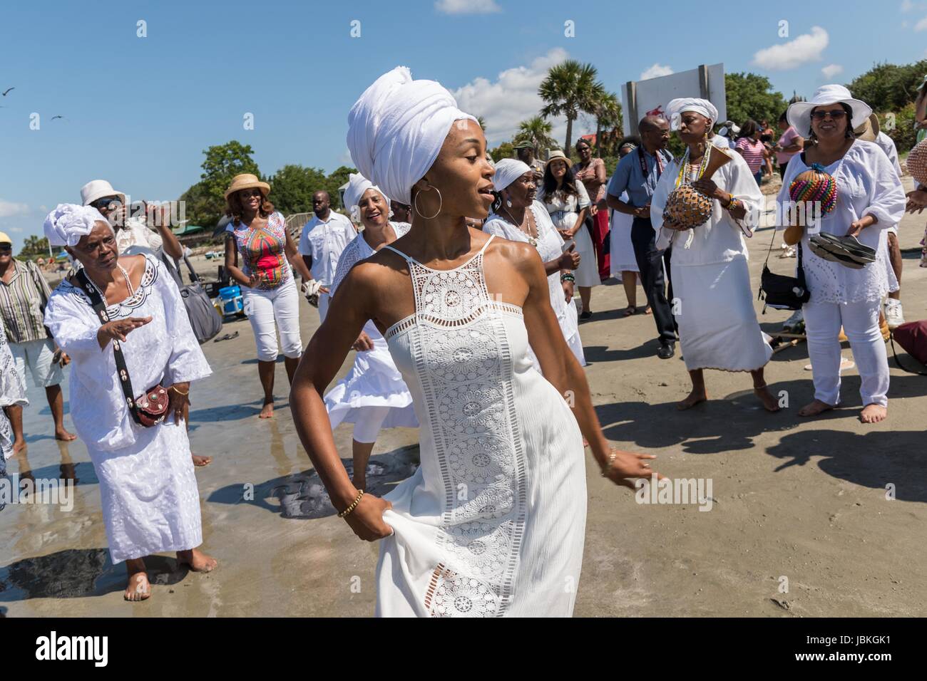 Descendants of enslaved Africans brought to Charleston in the Middle Passage dance to honor their relatives lost during a remembrance ceremony along the ocean front June 10, 2017 in Sullivan's Island, South Carolina. The Middle Passage refers to the triangular trade in which millions of Africans were shipped to the New World as part of the Atlantic slave trade. An estimated 15% of the Africans died at sea and considerably more in the process of capturing and transporting. The total number of African deaths directly attributable to the Middle Passage voyage is estimated at up to two million Afr Stock Photo