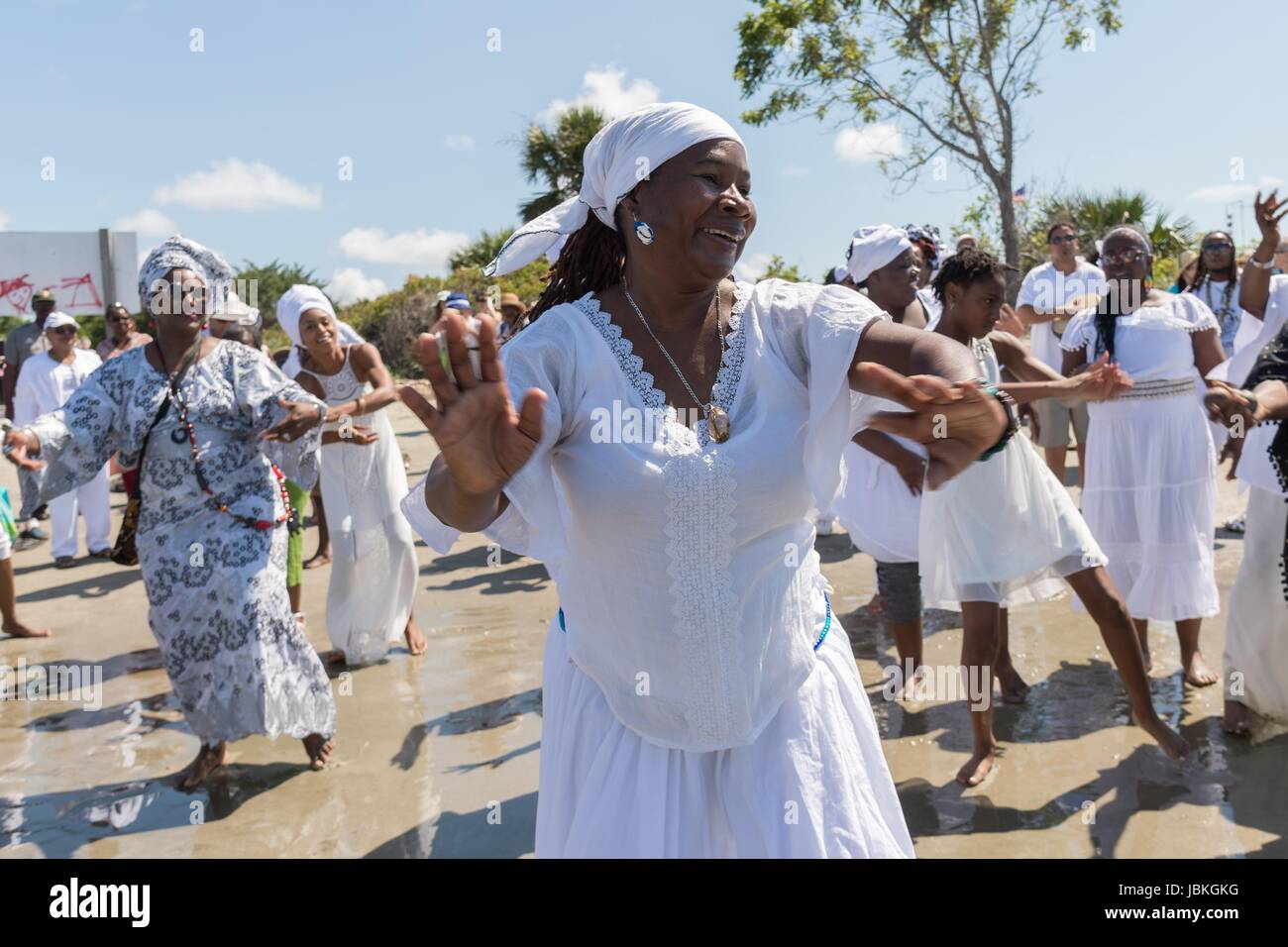 Descendants of enslaved Africans brought to Charleston in the Middle Passage dance to honor their relatives lost during a remembrance ceremony along the ocean front June 10, 2017 in Sullivan's Island, South Carolina. The Middle Passage refers to the triangular trade in which millions of Africans were shipped to the New World as part of the Atlantic slave trade. An estimated 15% of the Africans died at sea and considerably more in the process of capturing and transporting. The total number of African deaths directly attributable to the Middle Passage voyage is estimated at up to two million Afr Stock Photo