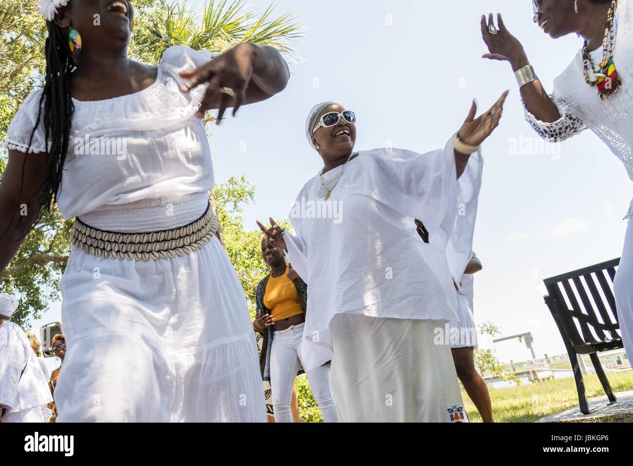 Descendants of enslaved Africans brought to Charleston in the Middle Passage dance to honor their relatives lost during a remembrance ceremony along the saltwater marsh June 10, 2017 in Sullivan's Island, South Carolina. The Middle Passage refers to the triangular trade in which millions of Africans were shipped to the New World as part of the Atlantic slave trade. An estimated 15% of the Africans died at sea and considerably more in the process of capturing and transporting. The total number of African deaths directly attributable to the Middle Passage voyage is estimated at up to two million Stock Photo