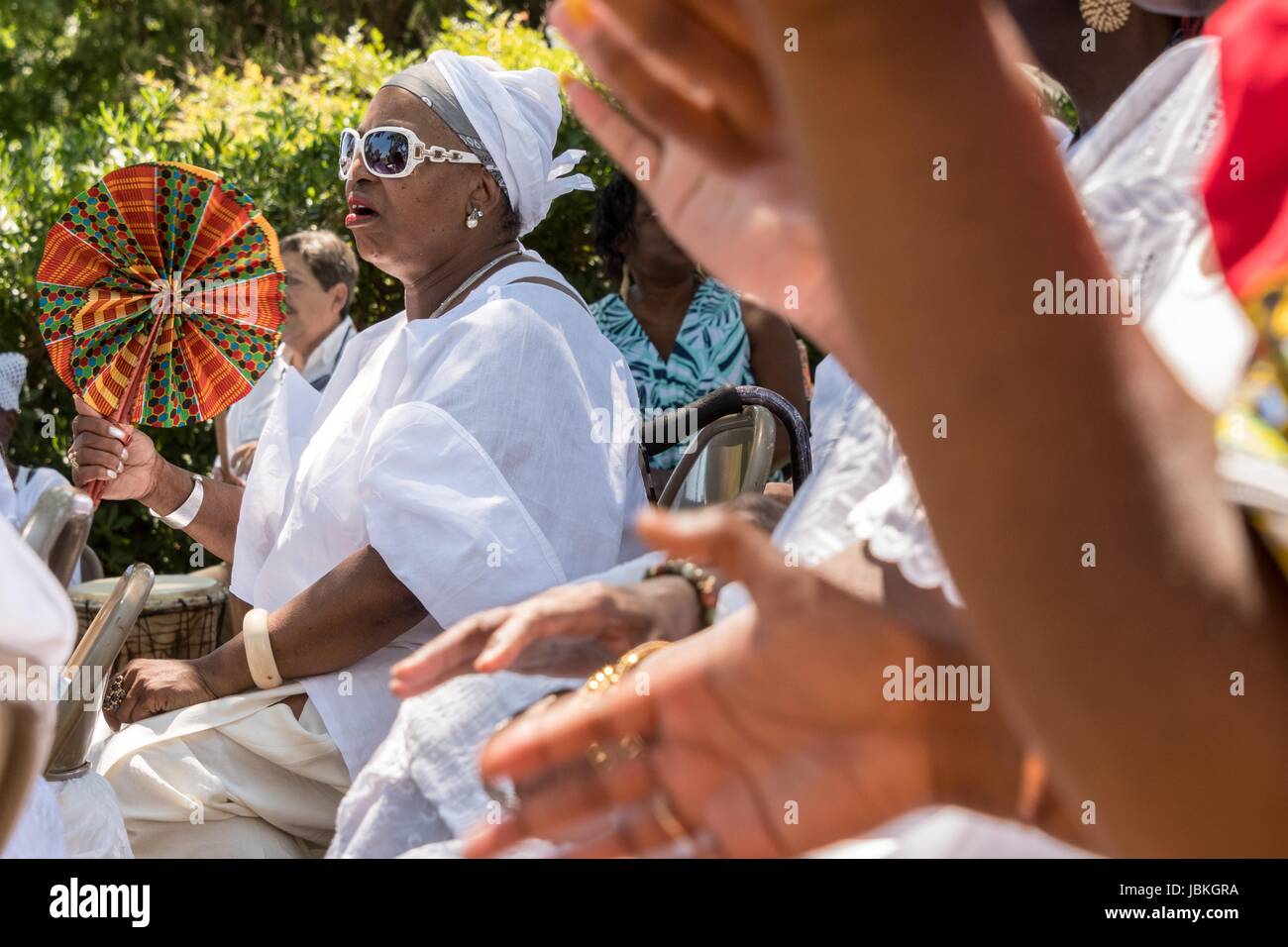 Descendants of enslaved Africans brought to Charleston in the Middle Passage sing praise songs during a remembrance ceremony at Fort Moutrie National Monument June 10, 2017 in Sullivan's Island, South Carolina. The Middle Passage refers to the triangular trade in which millions of Africans were shipped to the New World as part of the Atlantic slave trade. An estimated 15% of the Africans died at sea and considerably more in the process of capturing and transporting. The total number of African deaths directly attributable to the Middle Passage voyage is estimated at up to two million. Stock Photo